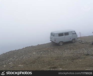 Car on the brink of an abyss in the fog of the clouds. Caucasus mountains