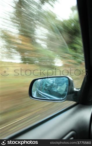 car on the road wiht motion blur background and rear view mirror