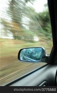 car on the road wiht motion blur background and rear view mirror