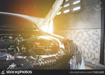 Car open hood in vehicle repair shop for maintenance service by mechanic,sunlight on background.