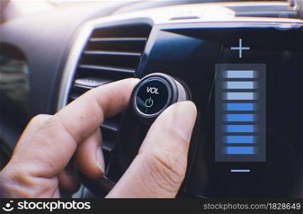 Car owner hand turning volume button of a car audio system in the car