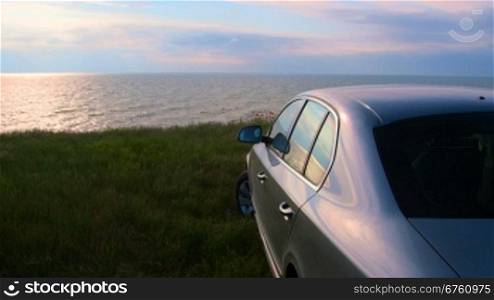 Car parked on the seashore at sunset, rear view
