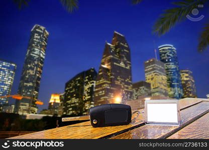 Car rental keys on wood table with blank paper in Houston night downtown