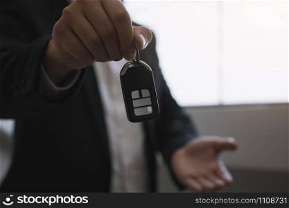 Car sales agent are car keys with the idea of buying a new car.