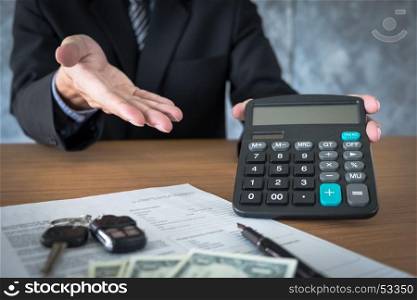 Car salesman holding a key and calculating a price at the dealership office