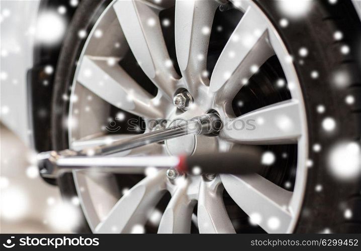 car service, repair and maintenance concept - screwdriver and wheel tire over snow. screwdriver and car wheel tire