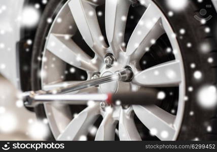 car service, repair and maintenance concept - screwdriver and wheel tire over snow. screwdriver and car wheel tire