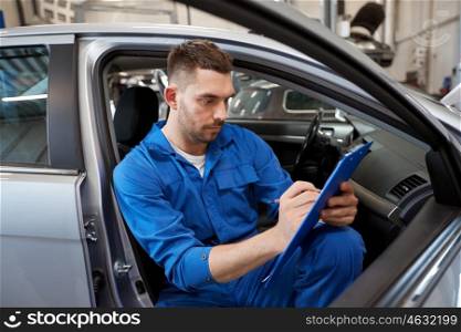 car service, repair, maintenance and people concept - auto mechanic man or smith with clipboard writing at workshop