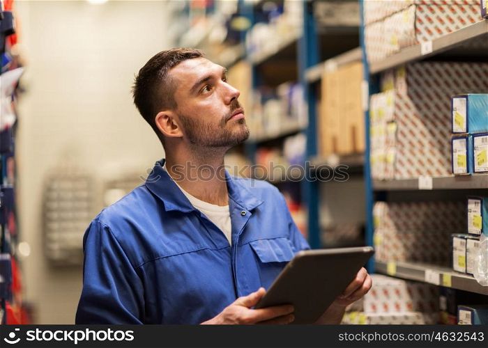 car service, repair, maintenance and people concept - auto mechanic man or smith with tablet pc computer looking for spares at workshop or warehouse