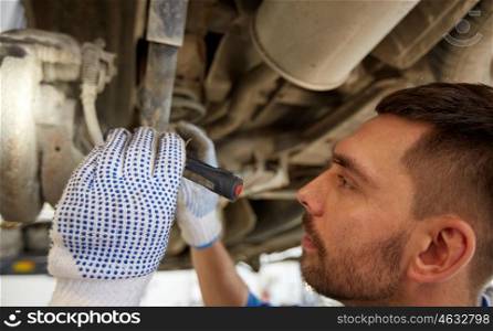 car service, repair, maintenance and people concept - auto mechanic man or smith with flashlight working at workshop