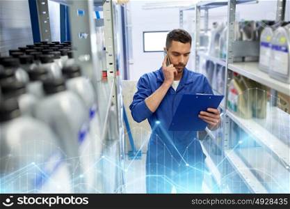 car service, repair, maintenance and people concept - auto mechanic man or smith with clipboard calling on smartphone at workshop or warehouse. auto mechanic calling on smartphone at car shop