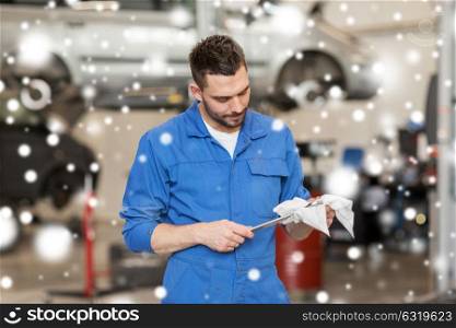 car service, repair, maintenance and people concept - auto mechanic man or smith with wrench at workshop over snow. auto mechanic or smith with wrench at car workshop