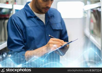 car service, repair, maintenance and people concept - auto mechanic man or smith writing to clipboard at workshop or warehouse. auto mechanic with clipboard at car workshop