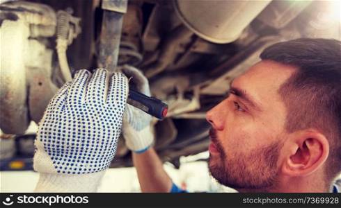 car service, repair, maintenance and people concept - auto mechanic man or smith with flashlight working at workshop. mechanic man with flashlight repairing car at shop
