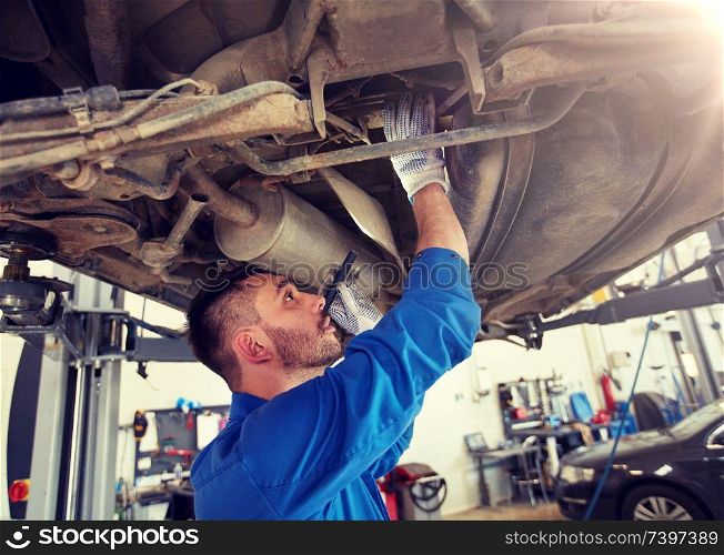 car service, repair, maintenance and people concept - auto mechanic man or smith with flashlight working at workshop. mechanic man with flashlight repairing car at shop