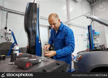 car service, repair, maintenance and people concept - auto mechanic man with wrench and lamp working at workshop