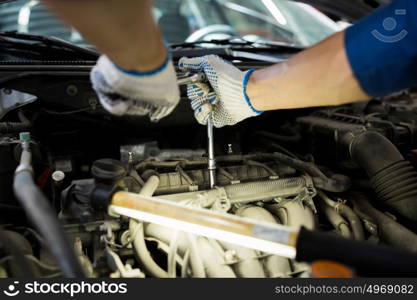 car service, repair, maintenance and people concept - auto mechanic man with wrench and lamp working at workshop. mechanic man with wrench repairing car at workshop