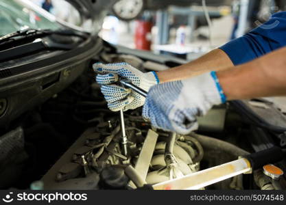 car service, repair, maintenance and people concept - auto mechanic man with wrench and lamp working at workshop. mechanic man with wrench repairing car at workshop