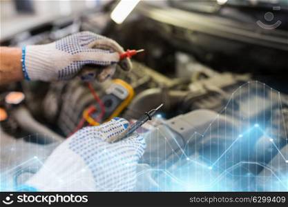 car service, repair, maintenance and people concept - auto mechanic man with digital multimeter testing battery at workshop. auto mechanic man with multimeter testing battery