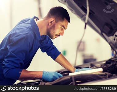 car service, repair, maintenance and people concept - auto mechanic man with l&working at workshop. mechanic man with l&repairing car at workshop