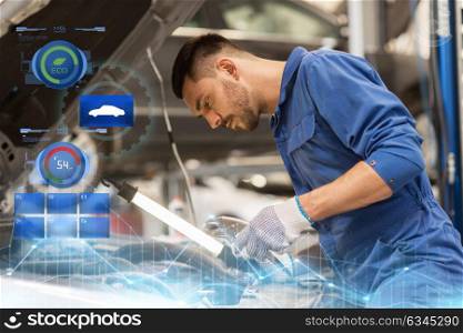 car service, repair, maintenance and people concept - auto mechanic man with lamp working at workshop. mechanic man with lamp repairing car at workshop