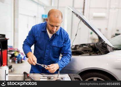 car service, repair, maintenance and people concept - auto mechanic man with wrench working at workshop