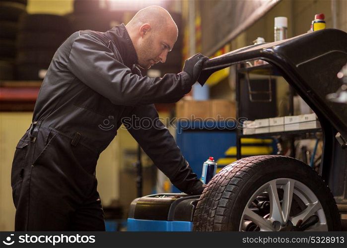 car service, repair, maintenance and people concept - auto mechanic man working with wheel balancing machine at workshop. auto mechanic balancing car wheel at workshop