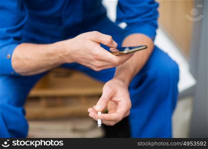 car service, repair, maintenance and people concept - auto mechanic smoking cigarette at workshop. auto mechanic smoking cigarette at car workshop