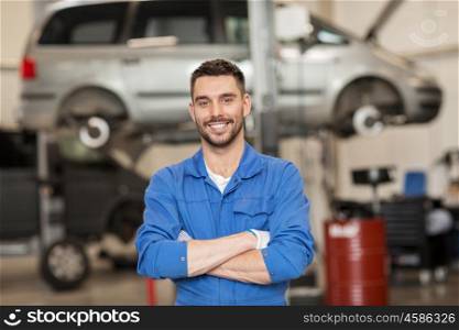 car service, repair, maintenance and people concept - happy smiling auto mechanic man or smith at workshop