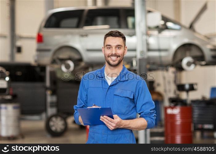 car service, repair, maintenance and people concept - happy smiling auto mechanic man or smith with clipboard at workshop