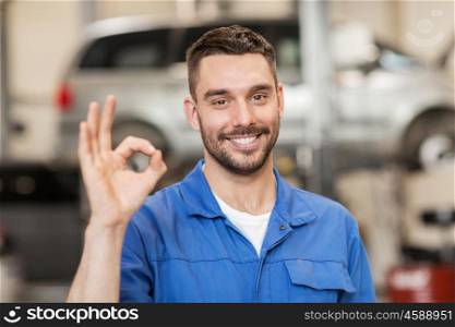 car service, repair, maintenance and people concept - happy smiling auto mechanic man or smith showing ok hand sign at workshop