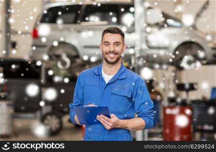 car service, repair, maintenance and people concept - happy smiling auto mechanic man or smith with clipboard at workshop over snow. happy mechanic man with clipboard at car workshop