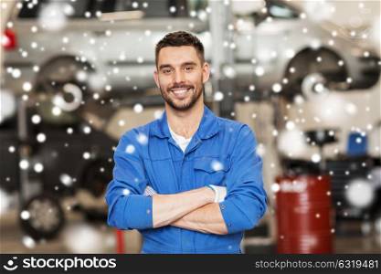 car service, repair, maintenance and people concept - happy smiling auto mechanic man or smith at workshop over snow. happy auto mechanic man or smith at car workshop