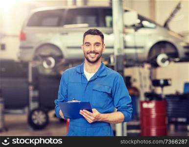 car service, repair, maintenance and people concept - happy smiling auto mechanic man or smith with clipboard at workshop. happy mechanic man with clipboard at car workshop