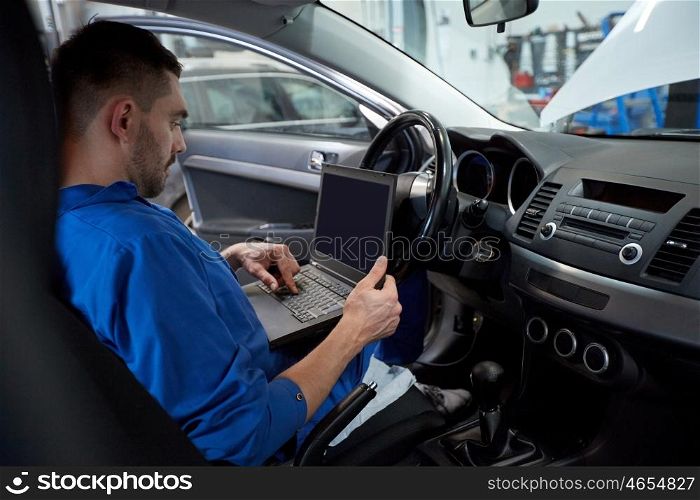 car service, repair, maintenance and people concept - mechanic man with laptop computer making system diagnostic at workshop