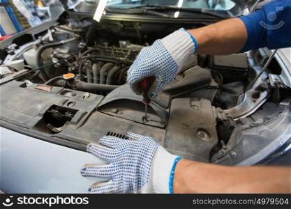 car service, repair, maintenance and people concept - mechanic man with wrench and lamp working at workshop. mechanic man with wrench repairing car at workshop