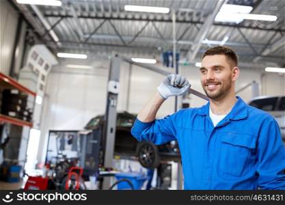 car service, repair, maintenance and people concept - smiling auto mechanic man or smith with wrench at workshop