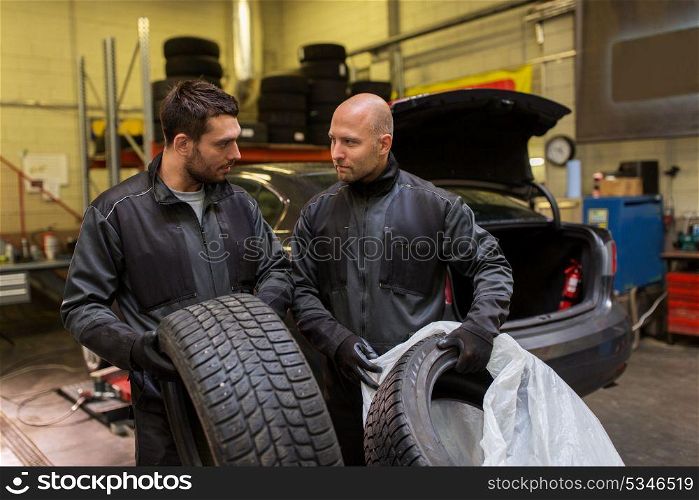 car service, repair, maintenance and people concept - two auto mechanics changing tires at workshop. auto mechanics changing car tires at workshop