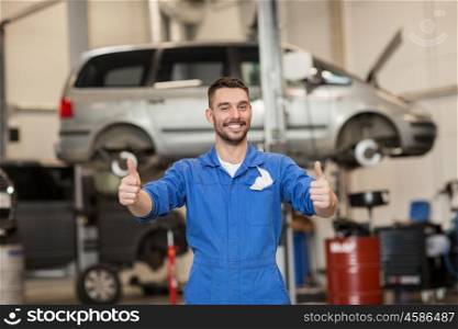 car service, repair, maintenance, gesture and people concept - happy smiling auto mechanic man or smith showing thumbs up at workshop