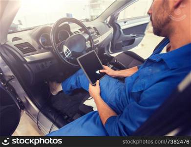 car service, repair, technology, maintenance and people concept - mechanic man with tablet pc computer making system diagnostic at workshop. mechanic man with tablet pc making car diagnostic