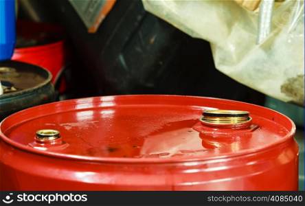 Car servicing oil change. Red oil barrel canister in mechanic garage auto service or shop. Industry detail.