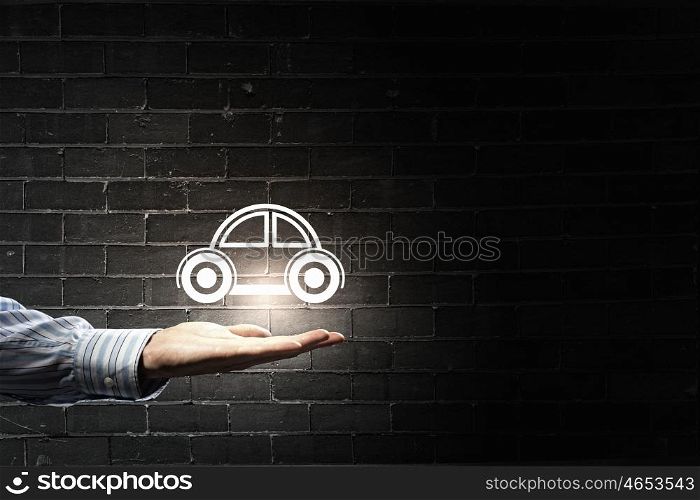 Car symbol in hand. Male hand holding car icon on dark background