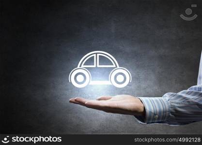 Car symbol in hand. Male hand holding car icon on dark background