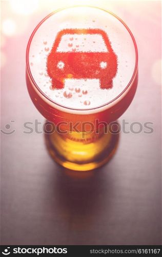 car symbol on foam in beer glass on black table, view from above