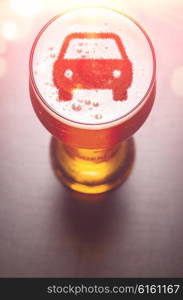 car symbol on foam in beer glass on black table, view from above