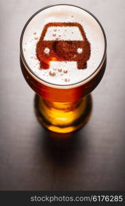 car symbol on foam in beer glass on black table, view from above