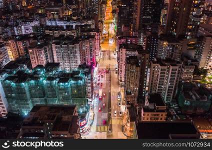 Car, taxi, and bus traffic on road intersection at night in Hong Kong downtown district, drone aerial top view. Street commuter, Asia city life, or public transportation concept