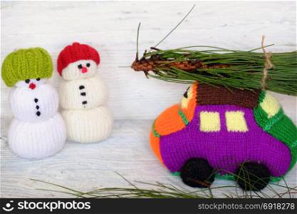 Car transport pine tree for Xmas decoration, knitted colorful cars on wooden, two snowman standing beside make funny Christmas background