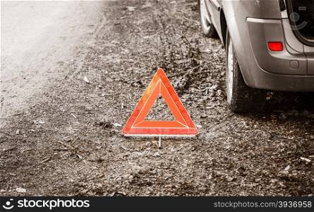Car transportation. Breakdown of car transporation. Closeup of red warning triangle sign symbol on the forest road.