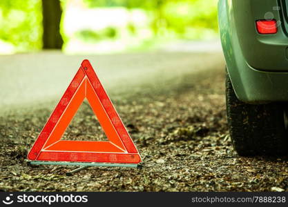 Car transportation. Breakdown of car transporation. Closeup of red warning triangle sign symbol on the forest road.